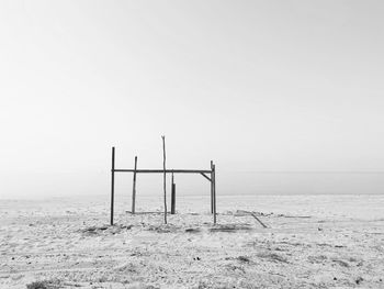 Wooden posts on beach against clear sky