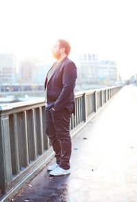 Full length of man standing on bridge against sky in city