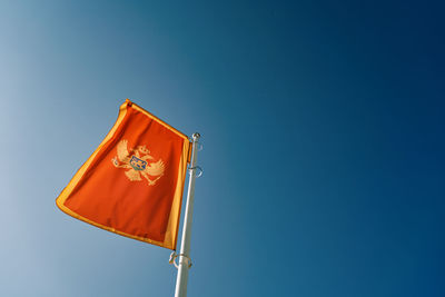 Low angle view of flag against clear blue sky