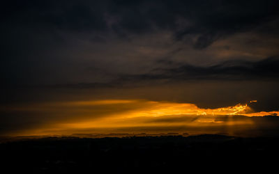 Silhouette landscape against dramatic sky during sunset