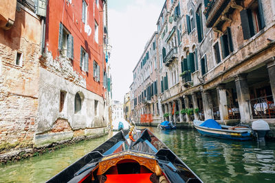 Boats in canal amidst buildings in city