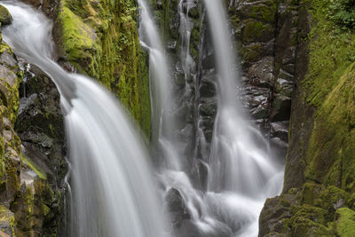 Gorgeous long exposure waterfalls in canyon with green mossy rocks.