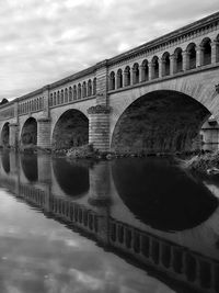 Reflection of bridge on river against sky