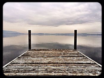 Pier on sea against cloudy sky