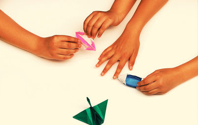 Cropped image of children playing with paper boats at table