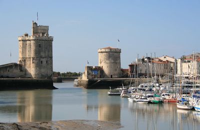 Sailboats in river against buildings in city