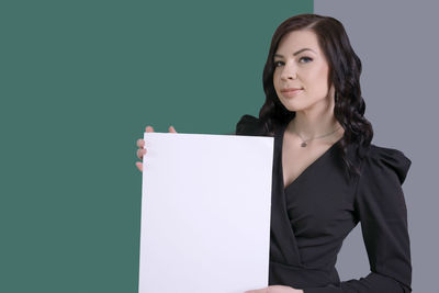 Portrait of young businesswoman standing against blue background