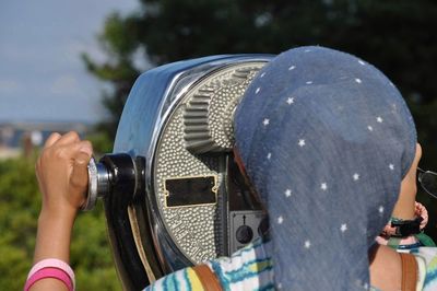 Close-up of woman looking through binoculars outdoors