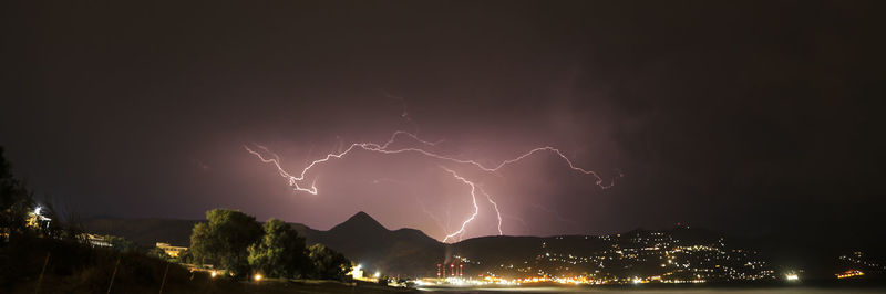 Firework display over illuminated city against sky at night