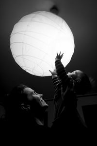 Side view of young woman looking at illuminated lamp