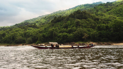 Boats moored on river by trees against sky