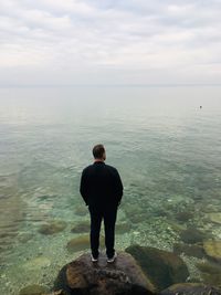 Rear view of man looking at sea against sky