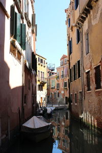 Canal amidst buildings in city against sky