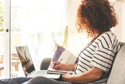 Midsection of woman holding mobile phone while sitting on table