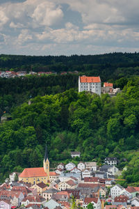 High angle view of townscape by trees and houses against sky