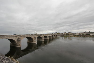 Arch bridge over river against sky