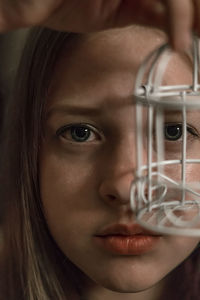 Close-up portrait of young woman holding small cage