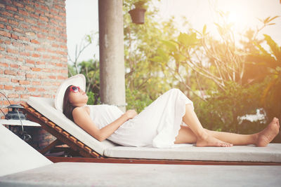 Full length of young woman relaxing on lounge chair at yard