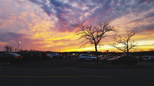 Silhouette cars on road against sky during sunset