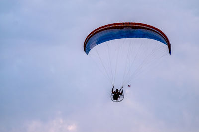 Low angle view of person paragliding against sky