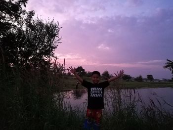 Man standing on field against sky during sunset