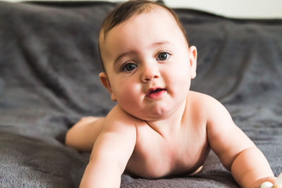 Portrait of cute baby girl lying on bed