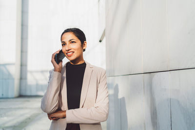 Portrait of young businesswoman standing against wall