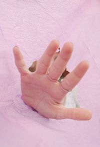 High angle view of person hand with pink petals on bed