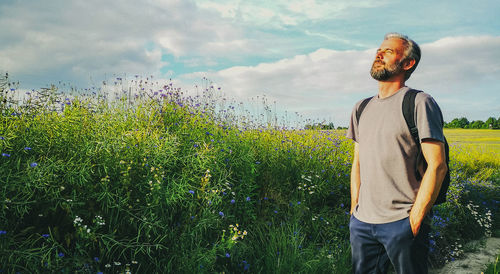 Young man standing on field against sky
