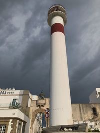 Low angle view of lighthouse by buildings against sky