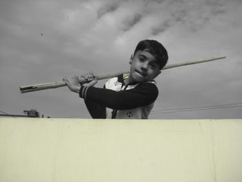 Portrait of boy holding camera against sky