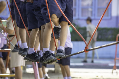 Low section of students standing on rope at playground