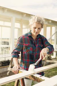 Woman painting wooden plank at farm