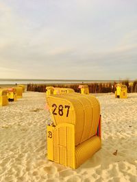 Hooded beach chairs on sand against sky