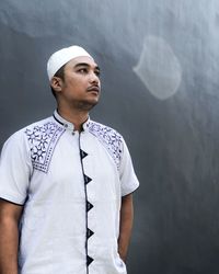 Portrait of young man looking away against wall
