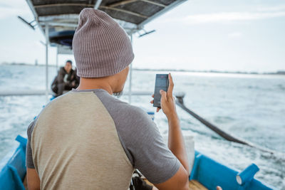 Rear view of man photographing sea