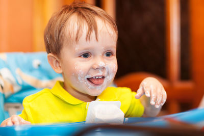 Close-up of happy boy with yogurt on face