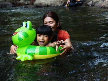 Happy mother with daughter swimming in river