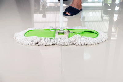 Low section of person with white shoe on floor at home