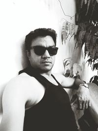 Young man wearing sunglasses standing against wall