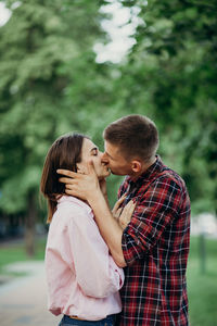 Side view of couple kissing while standing outdoors