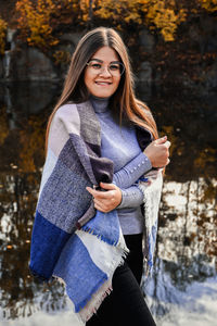 Close-up portrait of a woman in eyeglasses, with scarf on the lake. outside. happy smiling girl. 