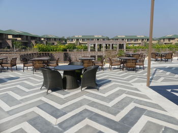 Chairs and tables in swimming pool against buildings