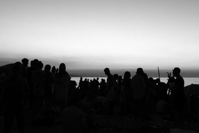 Silhouette people on beach against clear sky
