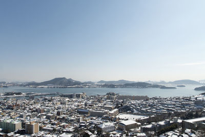 High angle view of townscape by sea against sky