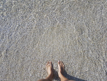 Low section of woman standing on sand