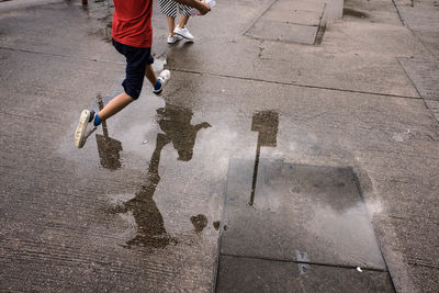 Low section of child running in puddle