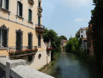 Canal amidst buildings in city against sky