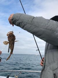 Man fishing in sea against sky