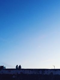 People standing against clear blue sky